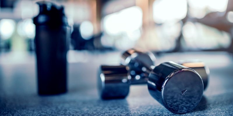 Metal dumb bells and black protein shaker bottle